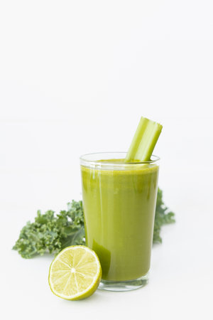 Vibrant green detox juice made from kale, celery, lemon, ginger, and green apple, placed on a white background with space for text.の写真素材