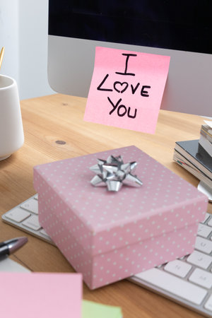 A romantic scene featuring a computer screen with a sticky note that says I Love You and a small gift box, symbolizing love and affection.の写真素材