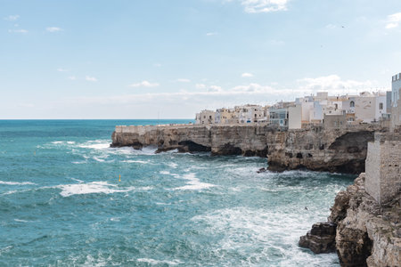 A scenic view of the coast in Polignano a Mare, Puglia, showing white buildings, rocky cliffs, and the clear blue waters of southern Italy.の写真素材