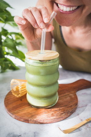 Enjoying Iced Matcha Latte in Natural Light â A Refreshing Moment of Balance and Wellnessの写真素材