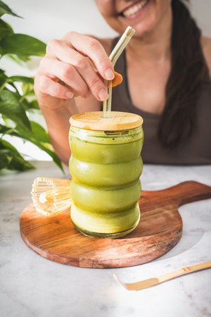 Enjoying Iced Matcha Latte in Natural Light â A Refreshing Moment of Balance and Wellnessの写真素材