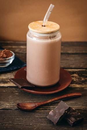 A glass cup filled with creamy hot chocolate and milk, freshly whisked to create a frothy texture.の写真素材