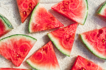 Top view of fresh watermelon slices arranged on a natural stone kitchen countertop