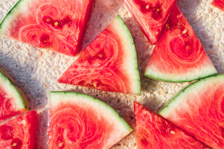 Top view of fresh watermelon slices arranged on a natural stone kitchen countertopの写真素材