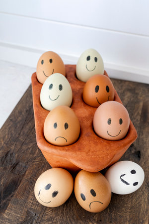 eggs painted with happy faces and one sad egg, symbolizing freshness and food quality differences. Concept of fresh and spoiled eggs, humor and healthy food choiceの写真素材
