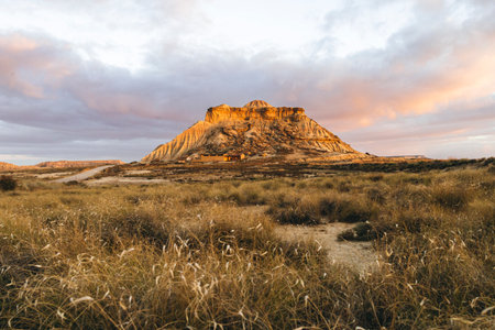 Beautiful sunrise over the semi-desert landscape of Bardenas Reales Natural Park in Navarra, Spain. Golden light illuminating the arid hills and eroded formations.の写真素材