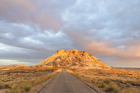 Beautiful sunrise over the semi-desert landscape of Bardenas Reales Natural Park in Navarra, Spain. Golden light illuminating the arid hills and eroded formations.の写真素材
