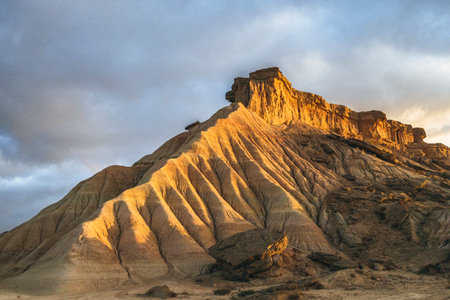 Beautiful sunrise over the semi-desert landscape of Bardenas Reales Natural Park in Navarra, Spain. Golden light illuminating the arid hills and eroded formations.の写真素材