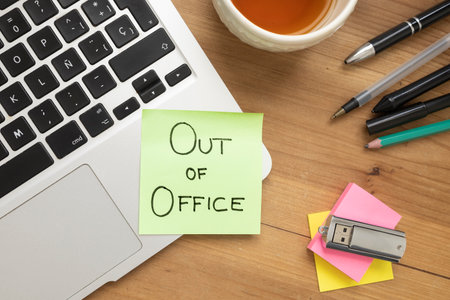 Green sticky note with handwritten text âOut of Officeâ placed on a desk, concept of vacation, rest, or work break.の写真素材