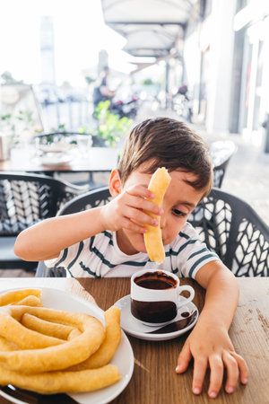 Child enjoying a snack of churros with a cup of thick hot chocolateの写真素材