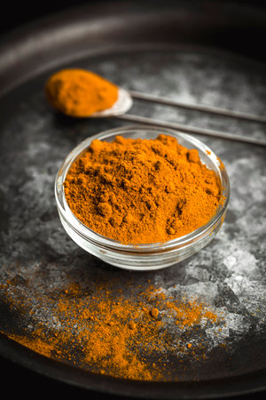Golden turmeric powder served on a dark plate over a contrasting background.の写真素材