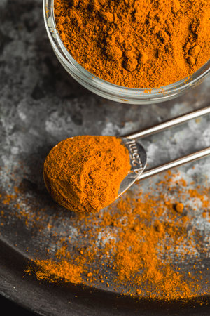 Golden turmeric powder served on a dark plate over a contrasting background.の写真素材