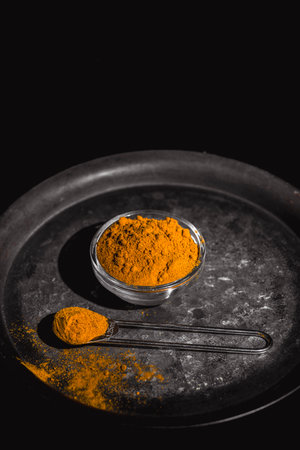 Golden turmeric powder served on a dark plate over a contrasting background.