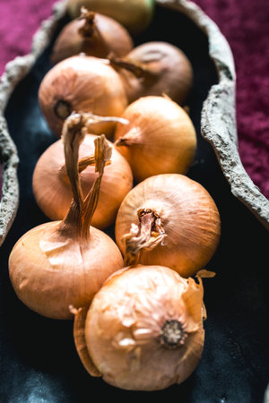 Close-up photograph of freshly harvested yellow onions, highlighting their natural golden skin and...