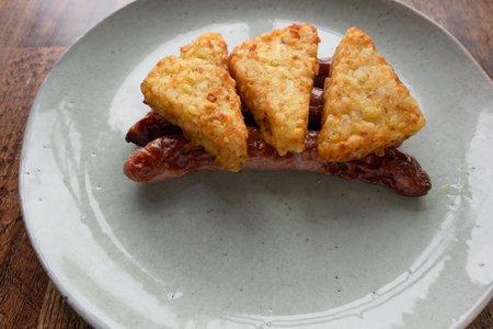 Simply breakfast hashbrown and sausage on a wooden table.の写真素材