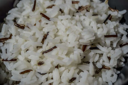 white parboiled black rice in a dark bowl plate with a reflex from sunlight