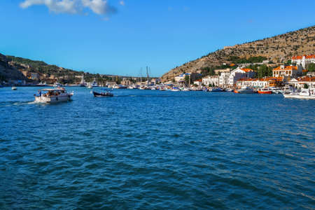 blue water with waves in bay of mountain town of Balaklava with marinas, white ships, boats and...