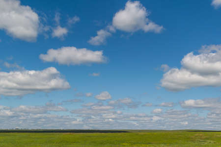 white bright fluffy clouds in blue sky with green field, open space