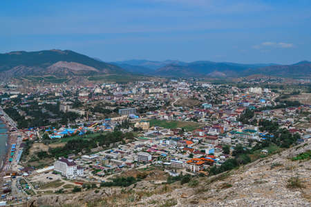 top view of resort green town on shore of Black Sea bay among mountains and rocks, summer