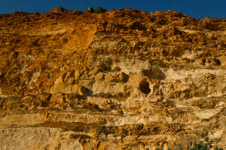 High red brown yellow sandy textured cliff of Fiolent with holes on the Black Sea coast in the light...