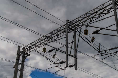 View of overhead electric lines used by train locomotives. Pole supporting the power lines used by electric train engines. Cloudy skyの写真素材