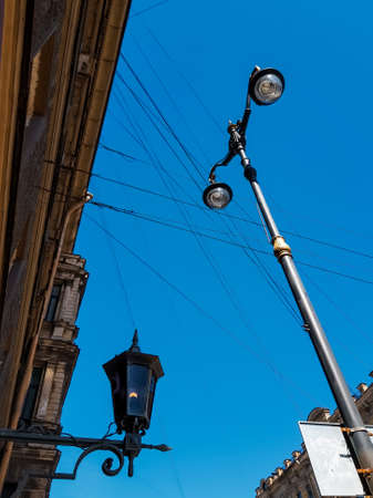 Old vintage black dark glass street lamp hanging on textured wall of beautiful building and lantern post, pillar in city of Saint Petersburg. Blue sky gradient. Contrastの写真素材