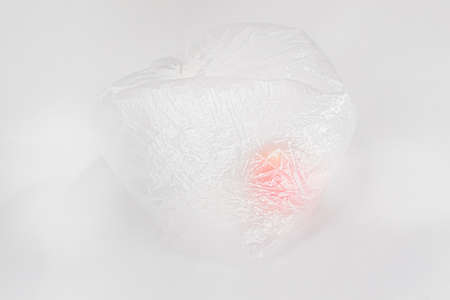 One red orange apple in transparent inflated plastic crumpled cellophane bag on white background....