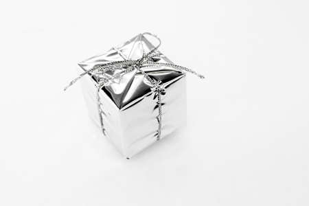 New year decoration - silver small gift, square shiny reflection toy on a white background....
