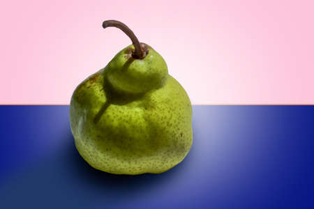 ripe green pear on colorful light orange pink blue gradient backgroundの写真素材