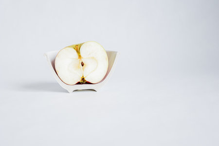 Concept. Sliced â€‹â€‹half of an apple in a broken half of a ceramic small plate on a...
