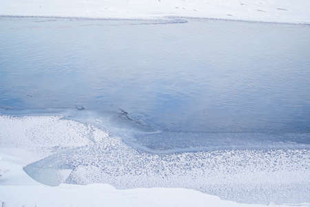 Winter blue river with sky reflection and frozen snowy banks. Minimalism. Natural north landscape. Top viewの写真素材