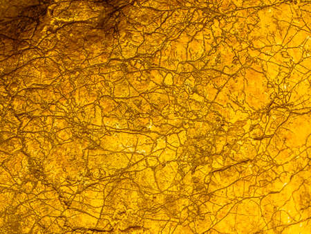 Gold texture rough leaf foil with cracks background. Shiny yellow abstract textured golden stone....