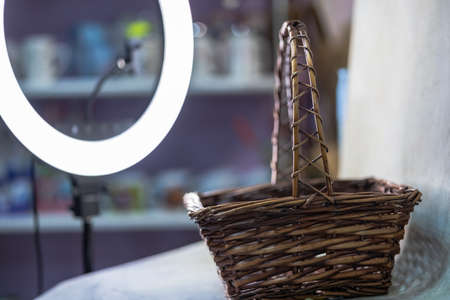 Dark brown wicker square basket with high handle in studio. Concept shooting. Round light lamp backgroundの写真素材