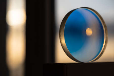 A transparent and round lens with blue highlights on the back of a sunset in the evening city.の写真素材
