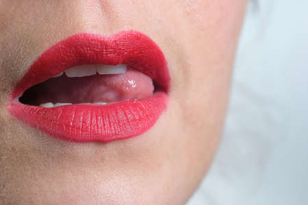 Close-up of a woman's lips with red lipstick on white background