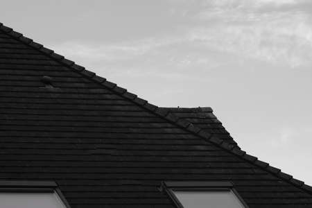 Roof of a house with black slate roof. Black and white photo.