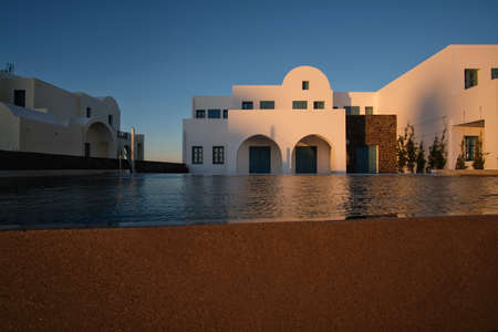 Luxury white villas with swimming pool at sunset.
