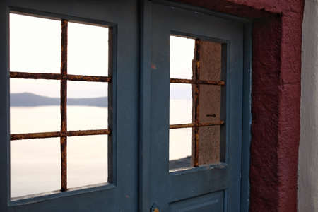 Old blue wooden door and window on the background of the sea.