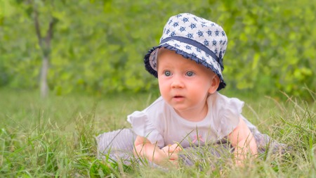 Toddler lying in the grass. Baby girl in hat, panama.の写真素材