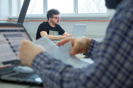 Young businessmen sitting at the desk. Business community working in open space office. Students at modern library. Business colleagues working at a busy open plan office.の写真素材