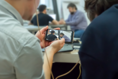 Monitoring education process with mobile phone. Record secretly on mobile phone. Mobile espionage. Hacker crack access code. Recording to a hidden camera. Listening to exam distantly on mobile screenの写真素材
