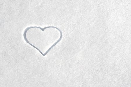 Heart symbol on the background of white snow. Sign of love on the snow. St. Valentines day background. Love concept.の写真素材
