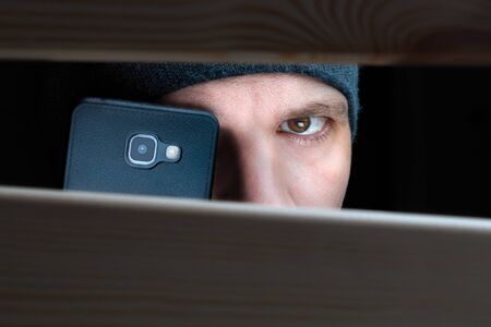 Mans eye looking through a hole between wooden boards. closeup. Information leak. Espionage concept....