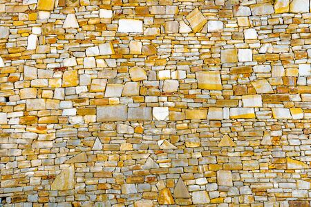 Stonewall background. Wall of stones with different size and shape. Old wall of ancient architecture. Original wall background. Stonewall background. Surface with asymmetrical stonesの写真素材