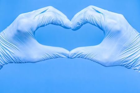 Heart shape made of hands in medical gloves. Heart made of medical gloves on blue background. Heart...