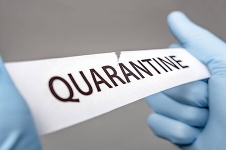 Hands in medical gloves tearing a piece of paper with QUARANTINE printed on it. Covid-19 Wuhan Novel Coronavirus pneumonia: COVID-19. Dangerous virus outbreak. Bioterrorismの写真素材