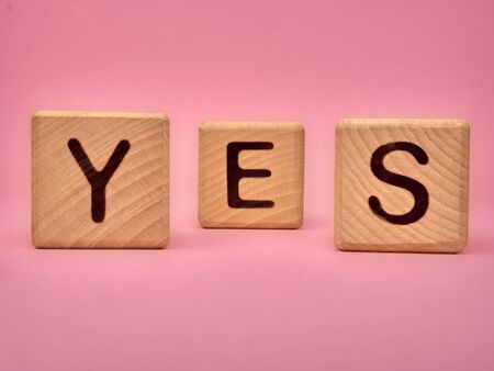 Wooden cubes with the word YES. Three wooden blocks with word YES on pink background. YES lettering on pink backgroundの写真素材