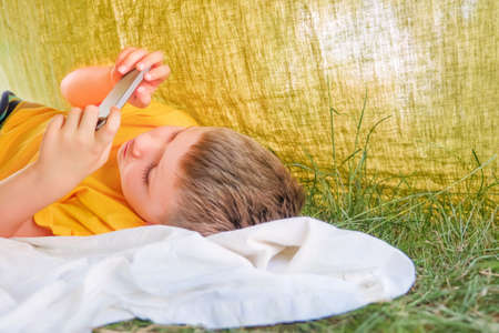 Child reading e-book. Online education. E-learning background. Little boy with cell phone playing video game. Alternative education. Quarantine and studying. E-courses background. Prepare to schoolの写真素材