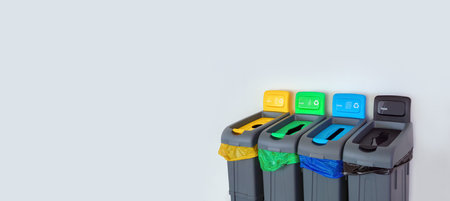 Colored Rubbish Containers for Separate Sorting of Garbage. Bins for Recycling Different Types of Waste Plastic, Glass, Paper, Trash near the White Wall. Sorting garbage Bin or Bags of Different Colorの写真素材