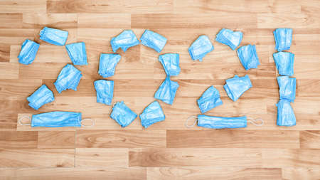 Top View of Numbers 2021 Made of Medical Face Protection Masks. Used Hygienic Masks Scattered on the...